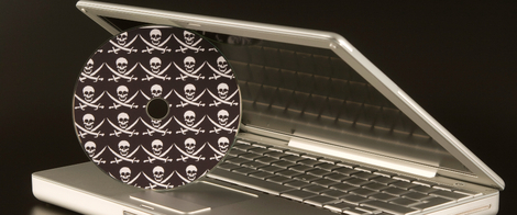 Изображение. Приоткрытый ноутбук и диск с пиратским ПО