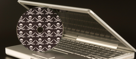 Изображение. Приоткрытый ноутбук и диск с пиратским ПО