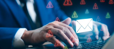 Изображение. Руки человека работают за ноутбуком на фоне предупреждающих знаков безопасности электронной почты