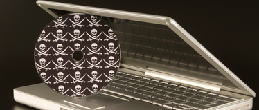 Изображение. Приоткрытый ноутбук и диск с пиратским ПО